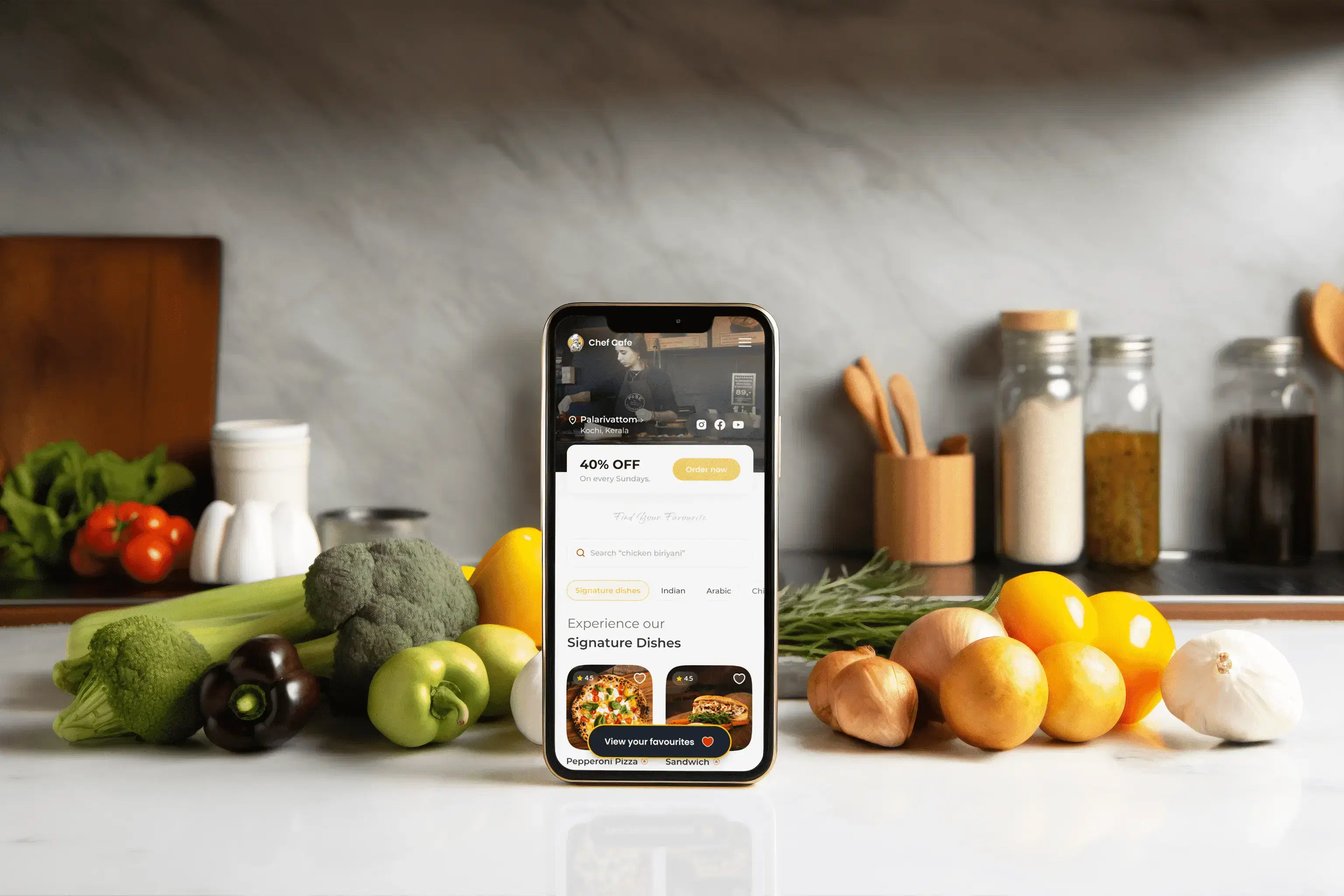 Foodee digital menu open on a phone, standing on a kitchen counter surrounded by fresh vegetables